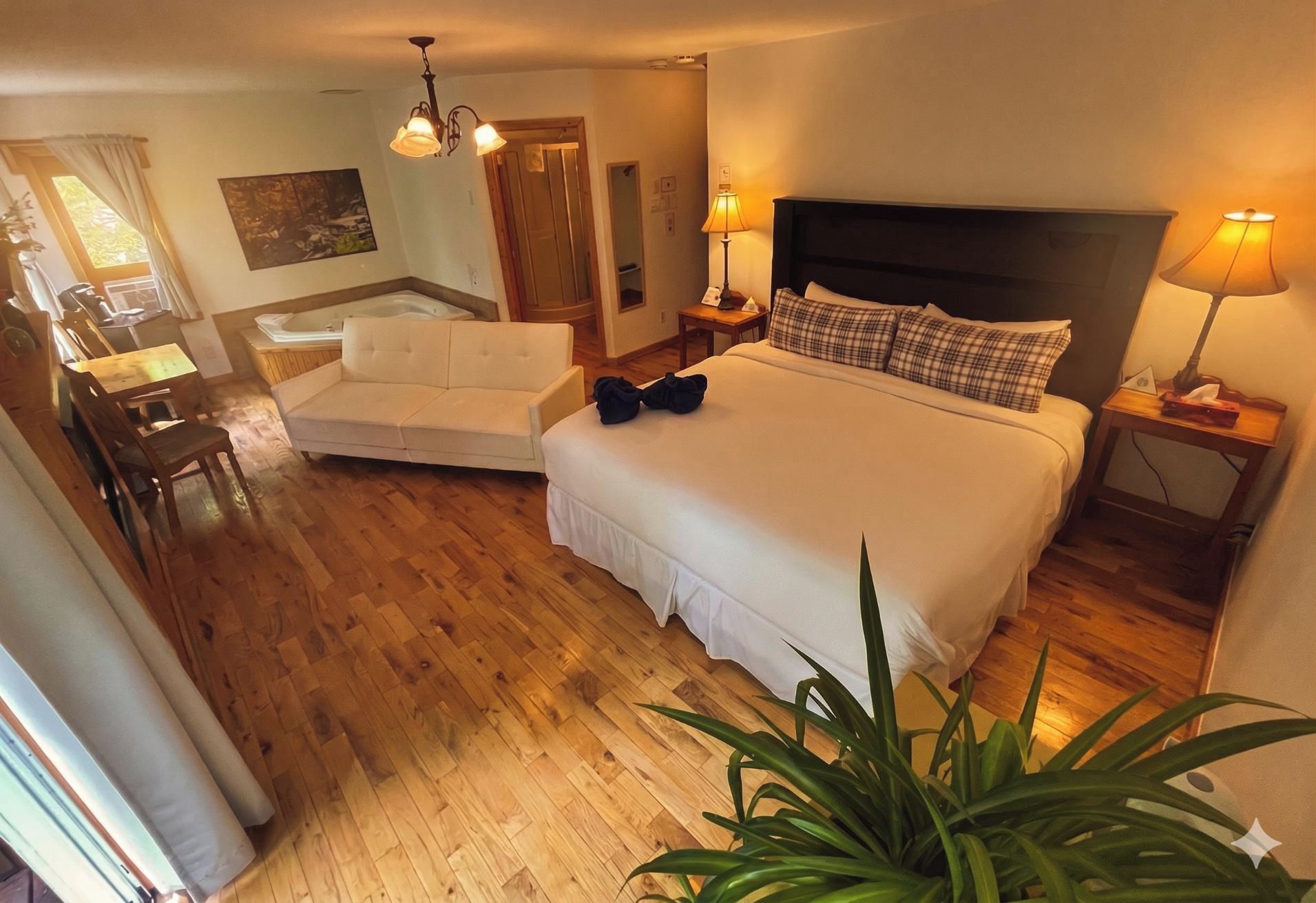 Habitación de hotel con cama, sofá, escritorio y zona de comedor.