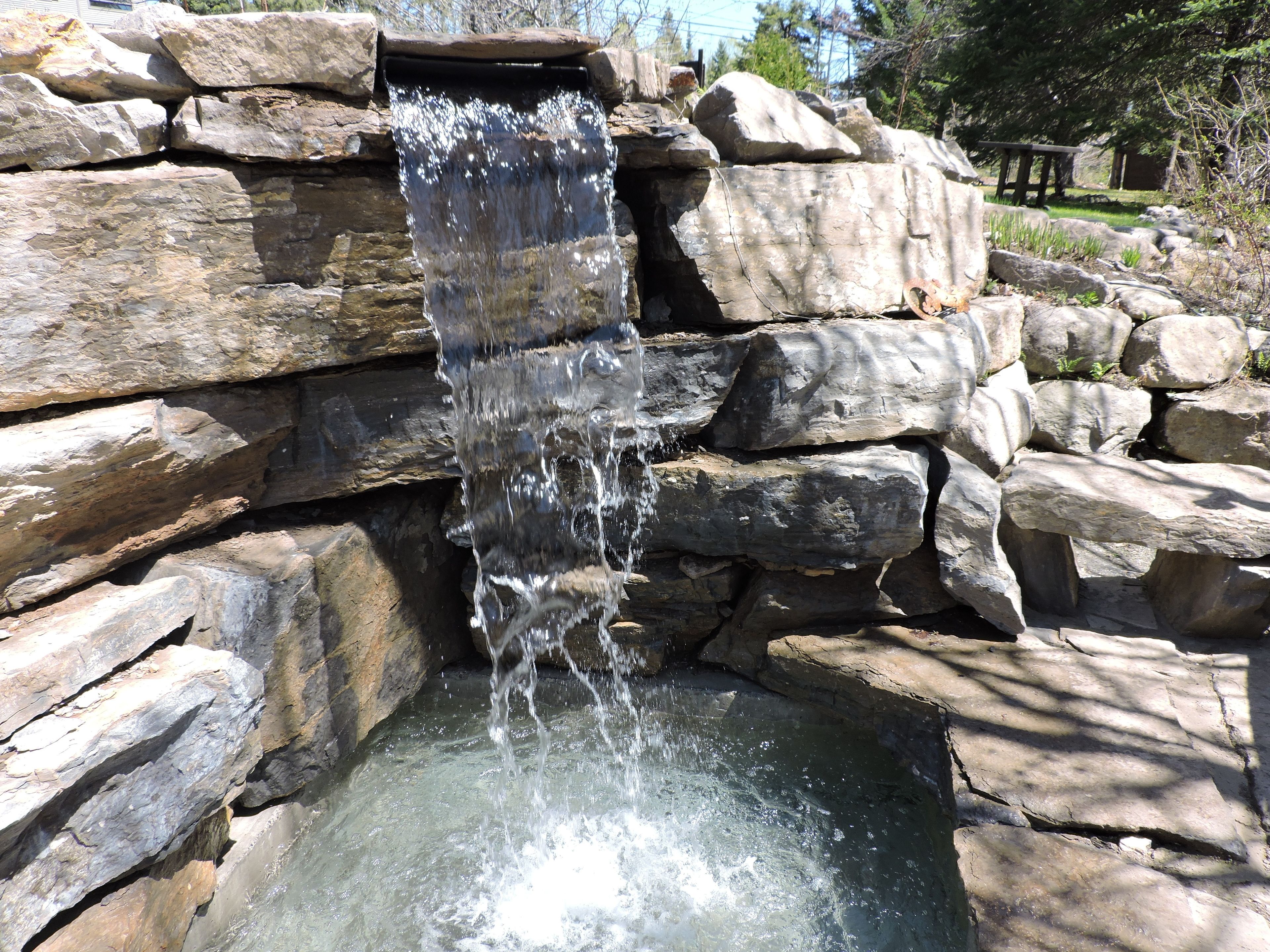 A waterfall cascading over a rocky structure into a pool.