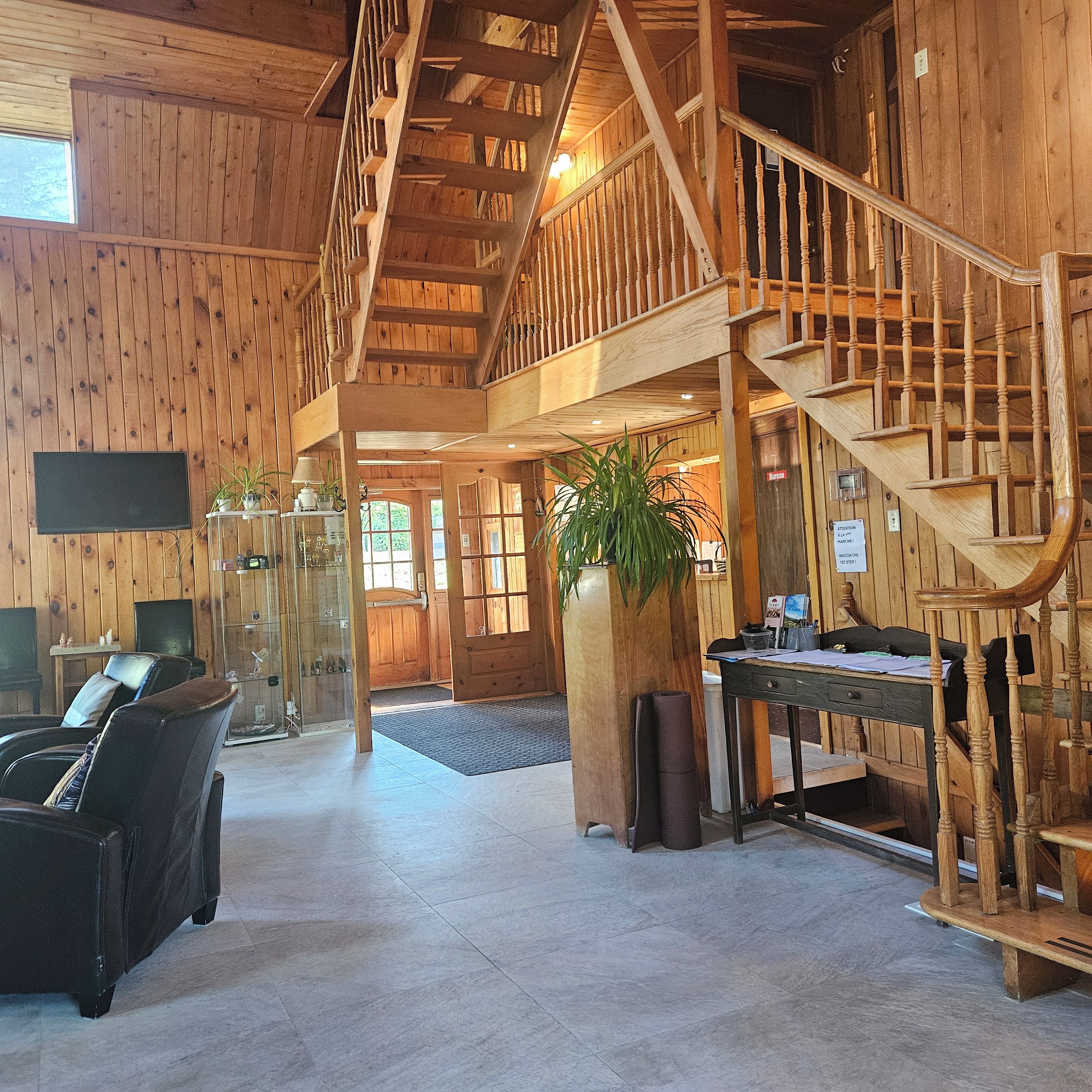 A wooden interior with a staircase, seating area, and a reception desk.