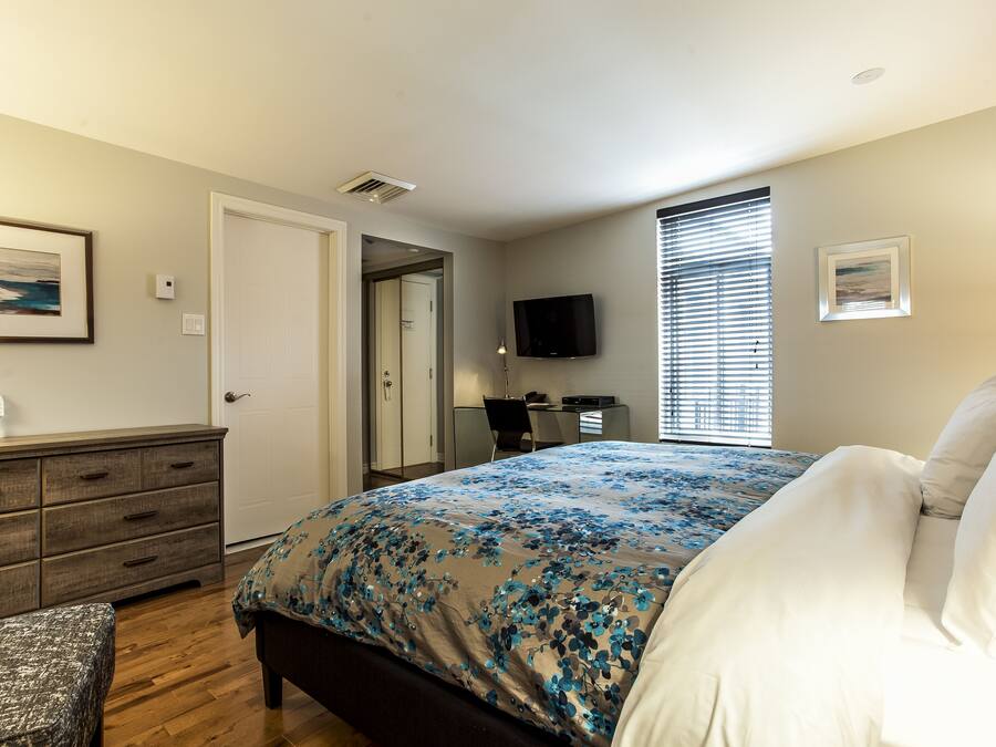 Quarto com cama, penteadeira, escrivaninha e televisão.