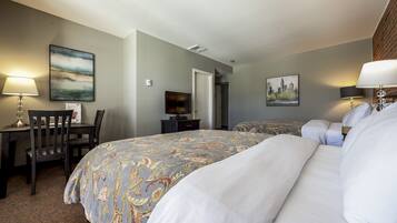 A hotel room with a large bed, a desk with a chair, a television, and two paintings on the walls.
