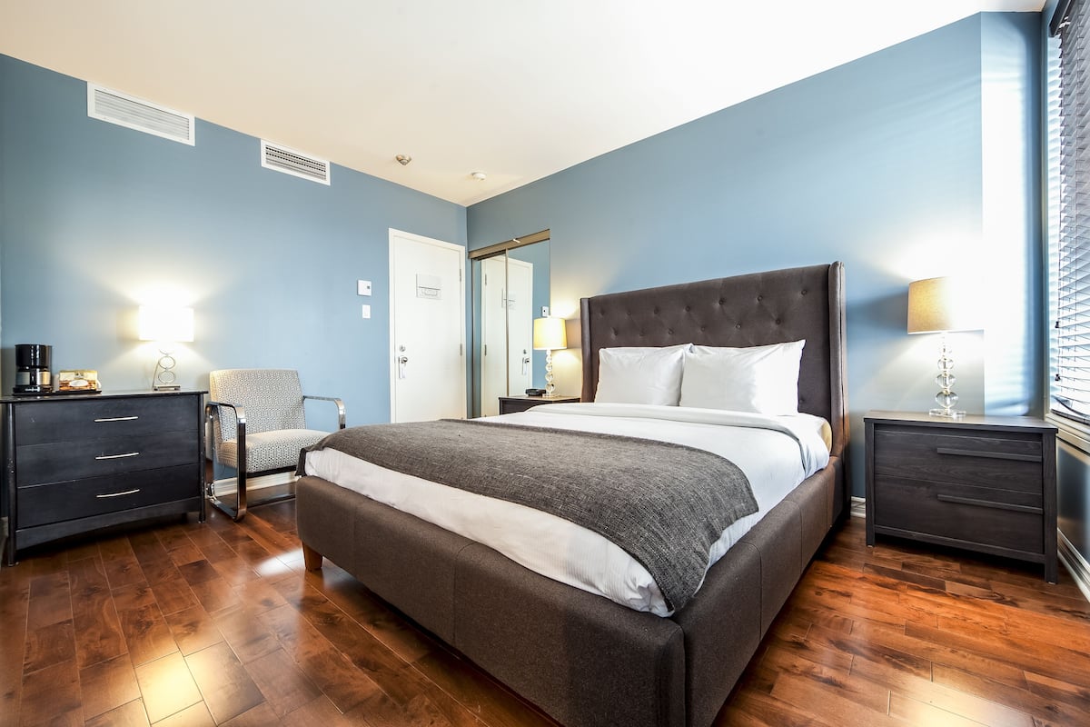 A bedroom with a large bed, a chair, a dresser, and a nightstand.