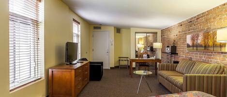 A hotel room with a bed, a TV, a desk, a chair, and a couch.