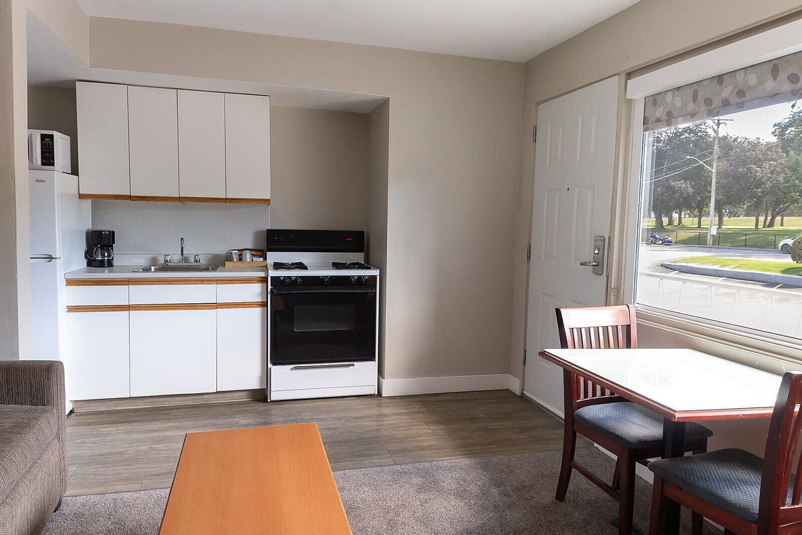 A compact kitchen with white cabinets, a stove, and a dining area with a table and chairs.