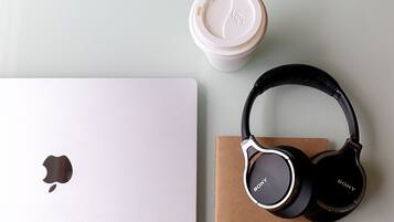 A laptop, headphones, and a coffee cup on a flat surface.