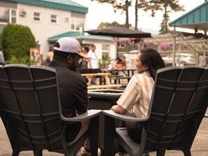 Two people seated at a table outdoors with a building and trees in the background.