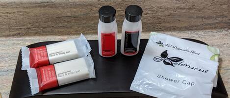 A tray with toiletries including a shower cap, a bar of soap, and two bottles of shampoo and conditioner.