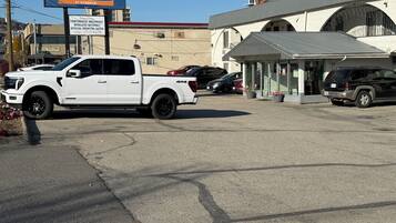 Un parking où sont garés un pick-up blanc et un SUV noir. On y voit un bâtiment avec une enseigne indiquant « Howard-Johnson By Wyndham ».