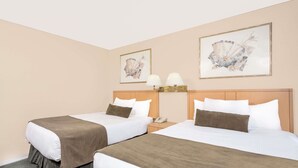 Habitación de hotel con dos camas, paredes color crema y obras de arte sobre ellas.