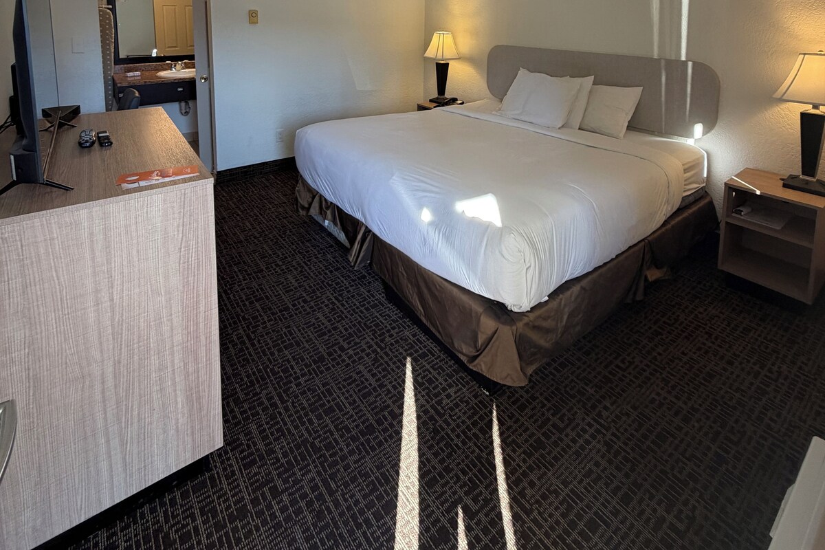 A hotel room with a bed, bedside tables, a desk, and a mirror.
