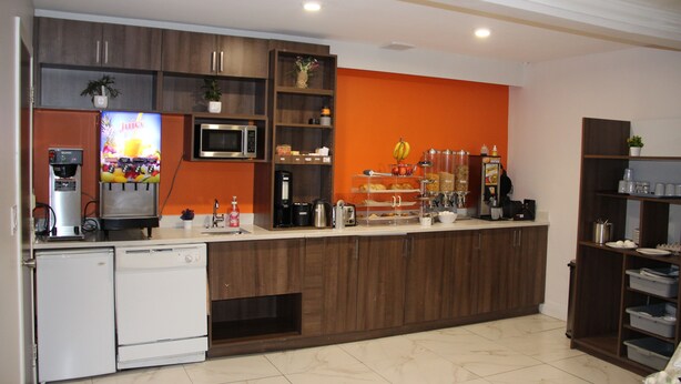 Una cocina moderna con microondas integrado, cafetera y dispensador de zumo.