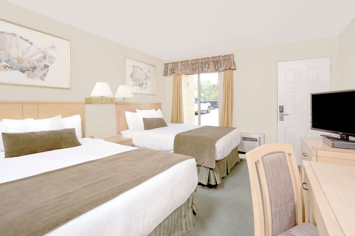 Een hotelkamer met twee bedden, een televisie, een bureau en een stoel.