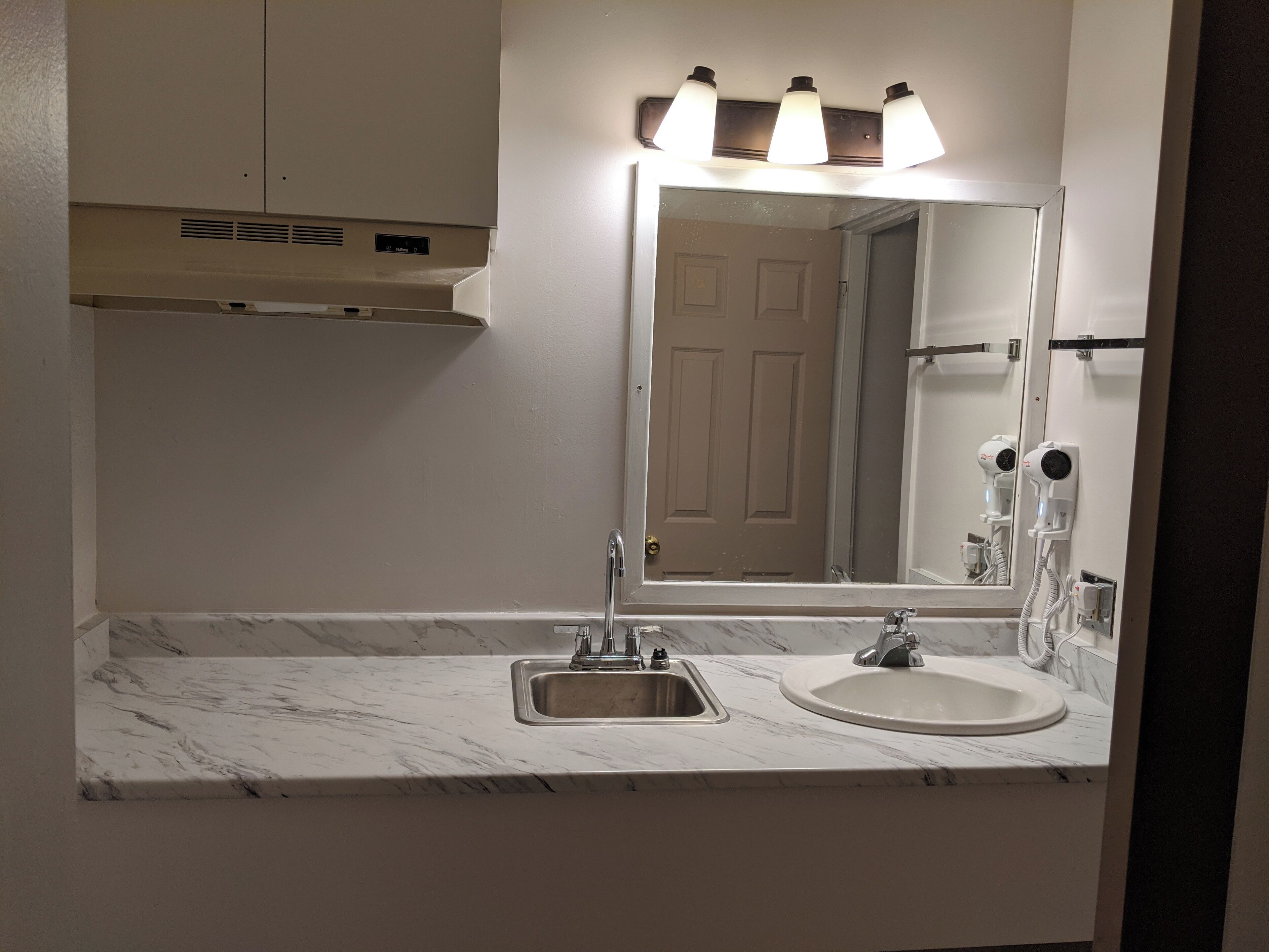 Un bagno con lavandino, specchio e asciugacapelli.