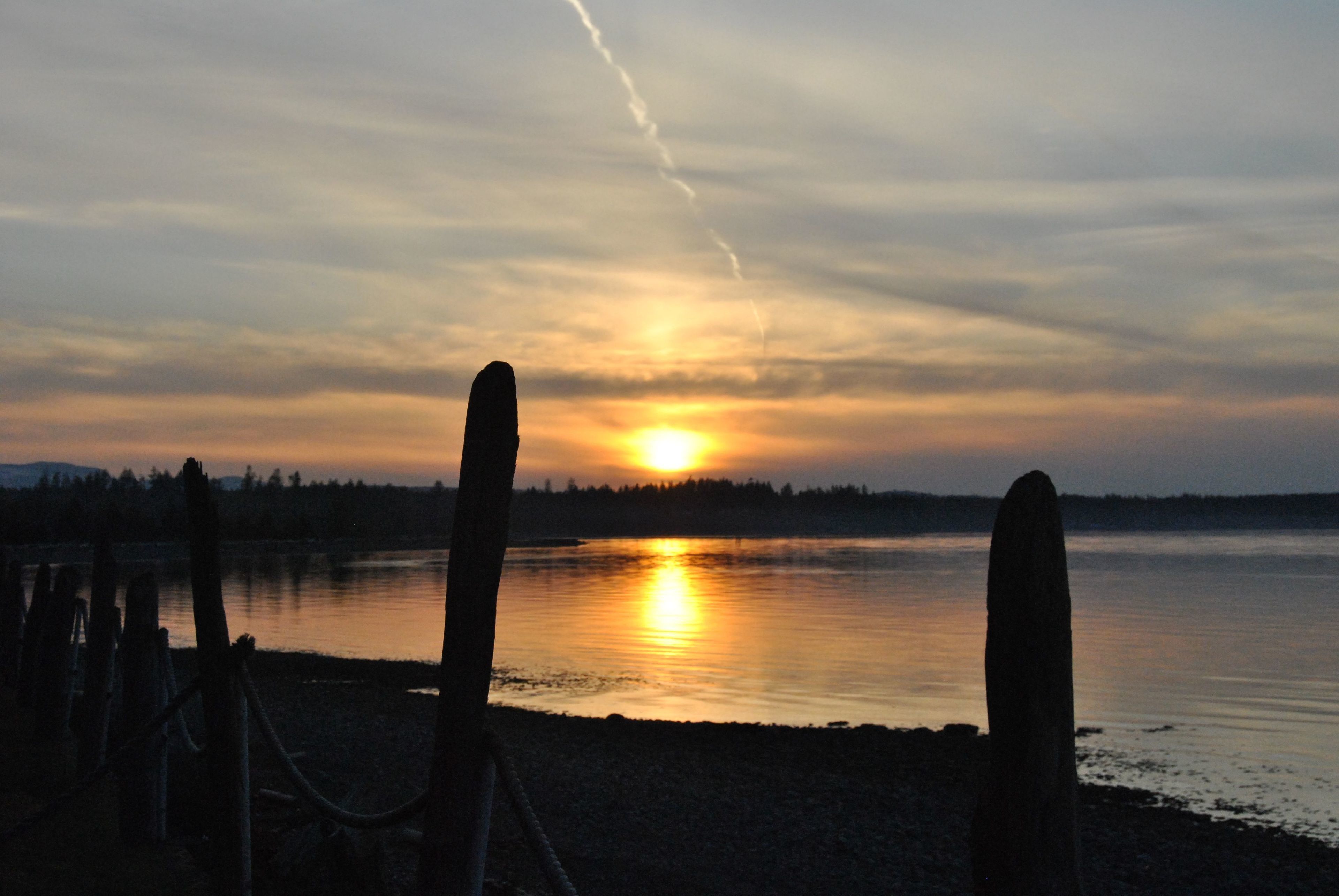 A sunset over a calm lake with a wooden fence in the foreground.