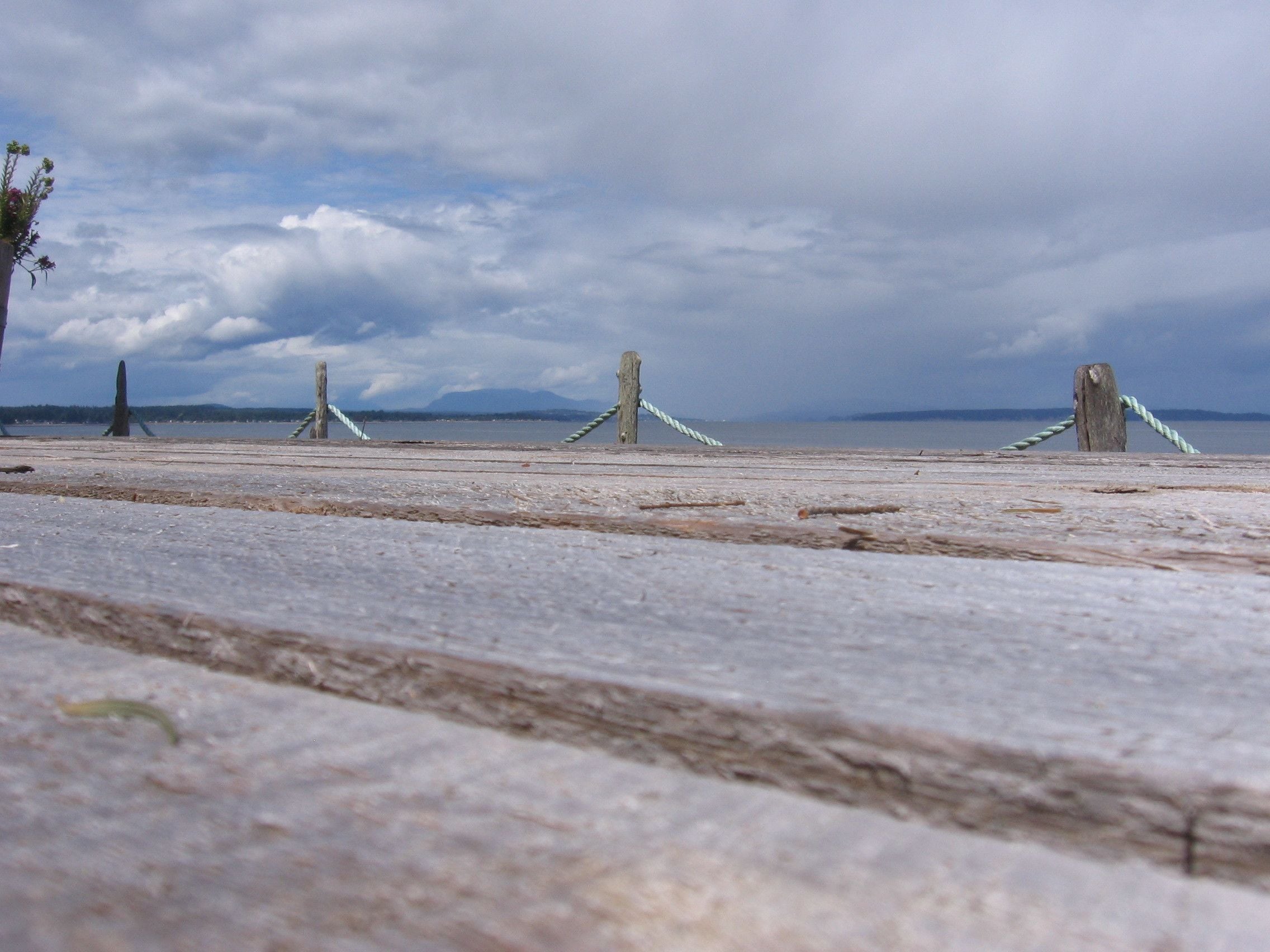 A beach with wooden posts and ropes, a clear sky, and distant mountains.