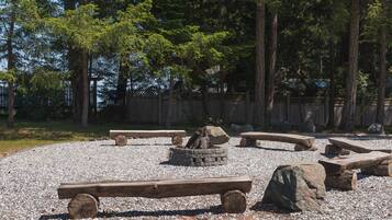 A gravel area with wooden benches and a fire pit.