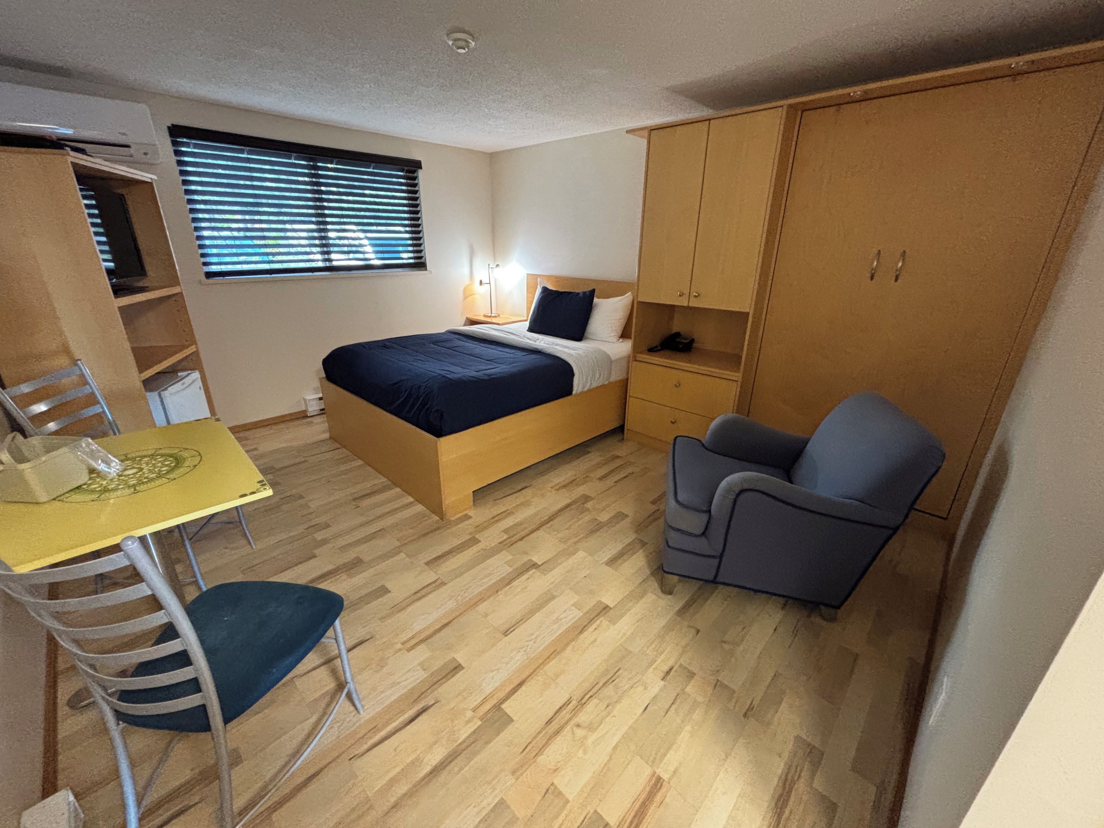 A compact room with a bed, a desk, a chair, and a wardrobe.