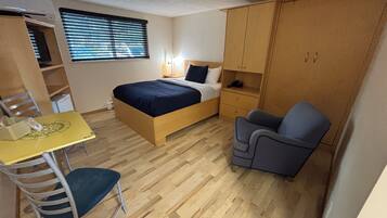 A compact room with a bed, a desk, a chair, and a wardrobe.