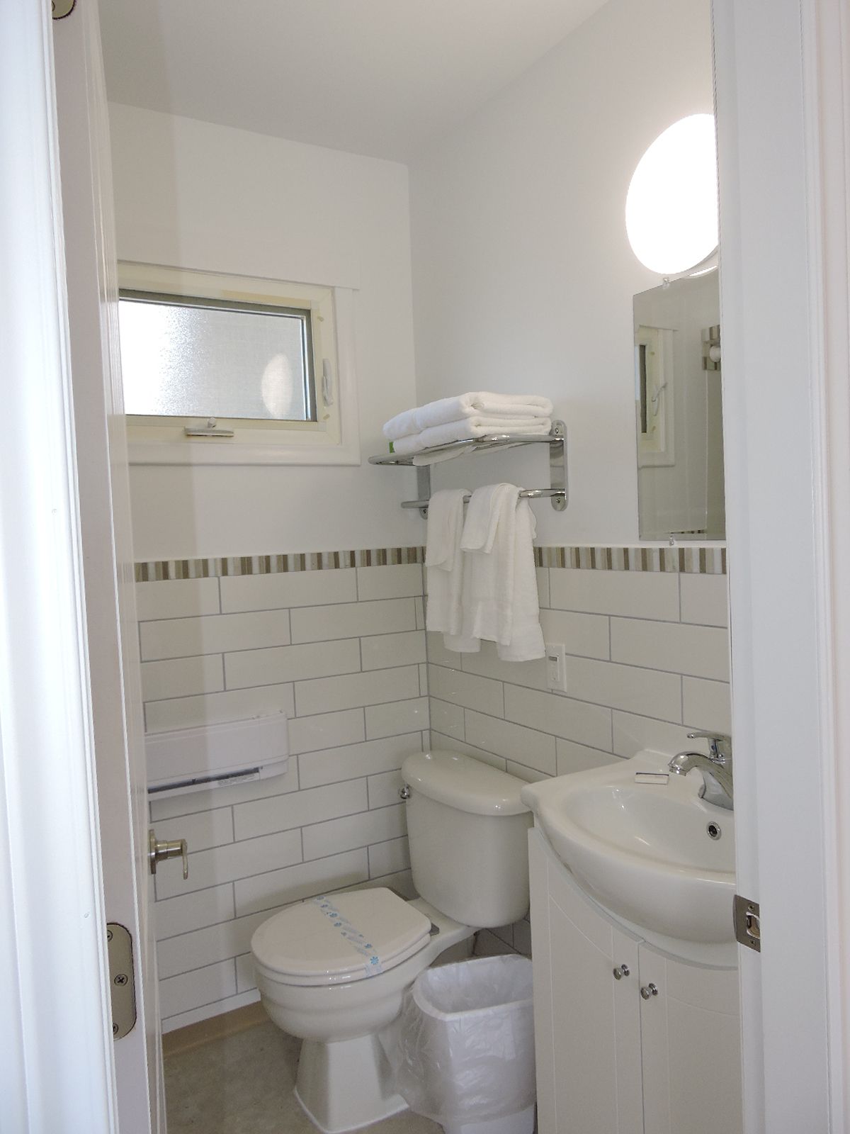 A small, clean bathroom with a toilet, sink, and a mirror above the sink.