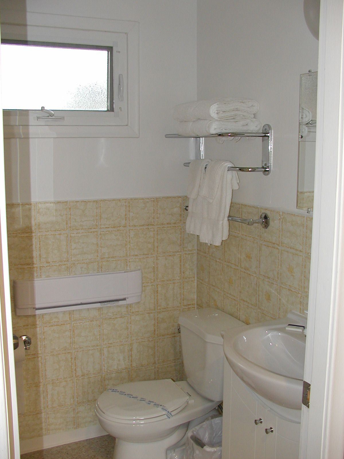 A bathroom with a toilet, a sink, a towel rack, and a window.