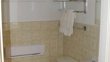 A bathroom with a toilet, a sink, a towel rack, and a window.