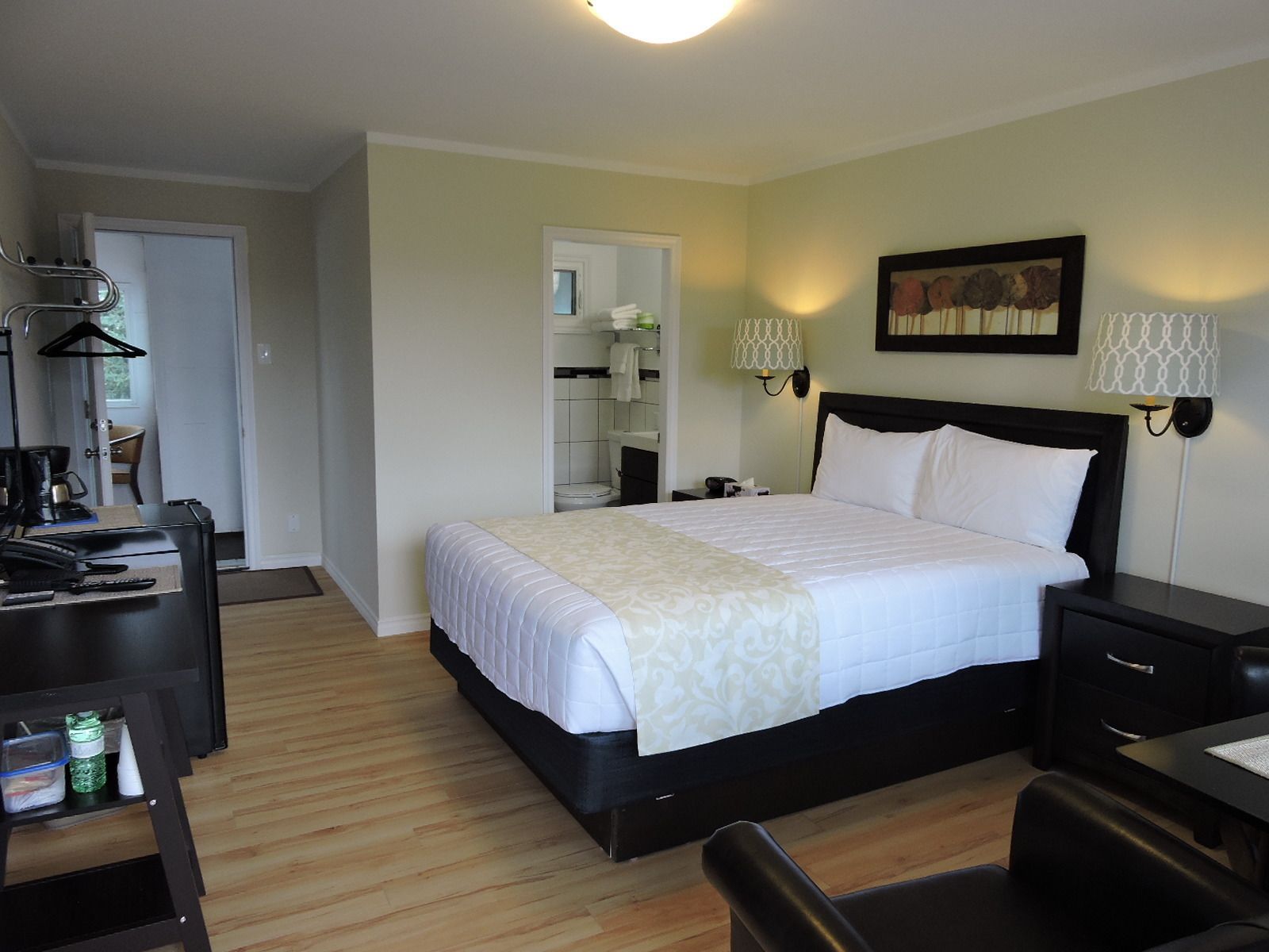 A neatly arranged hotel room with a large bed, bedside tables, a desk with a chair, and a wardrobe.