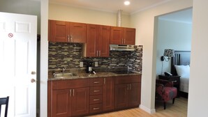 A compact kitchen with wooden cabinets, a tiled backsplash, and a built-in oven. - Almo Court Motel (Cranbrook)