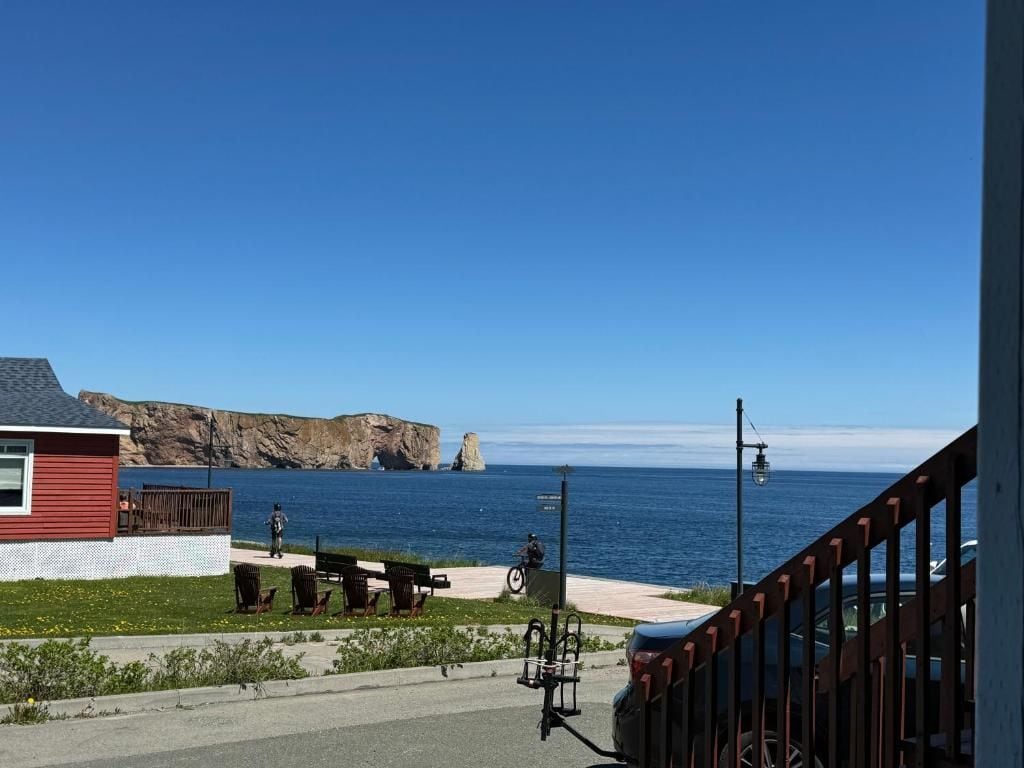 A coastal view with a red building, a bench, and a bicycle parked by the road.