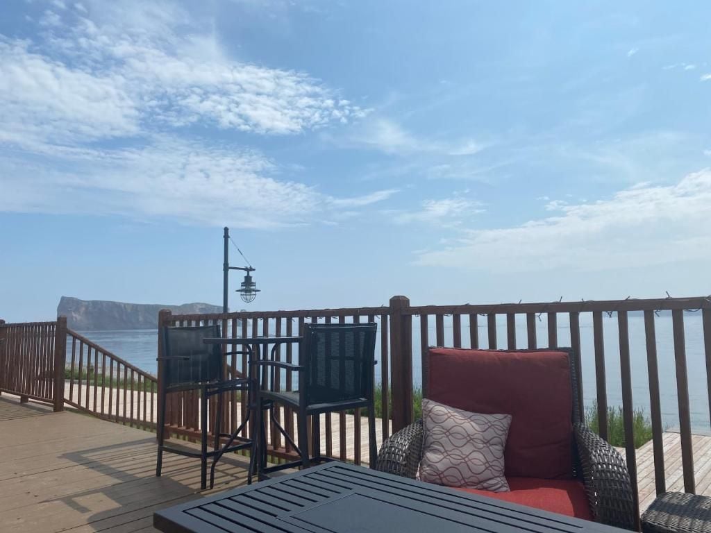 Een houten terras met uitzicht op zee, een stoel, een tafel en een rode kussen.