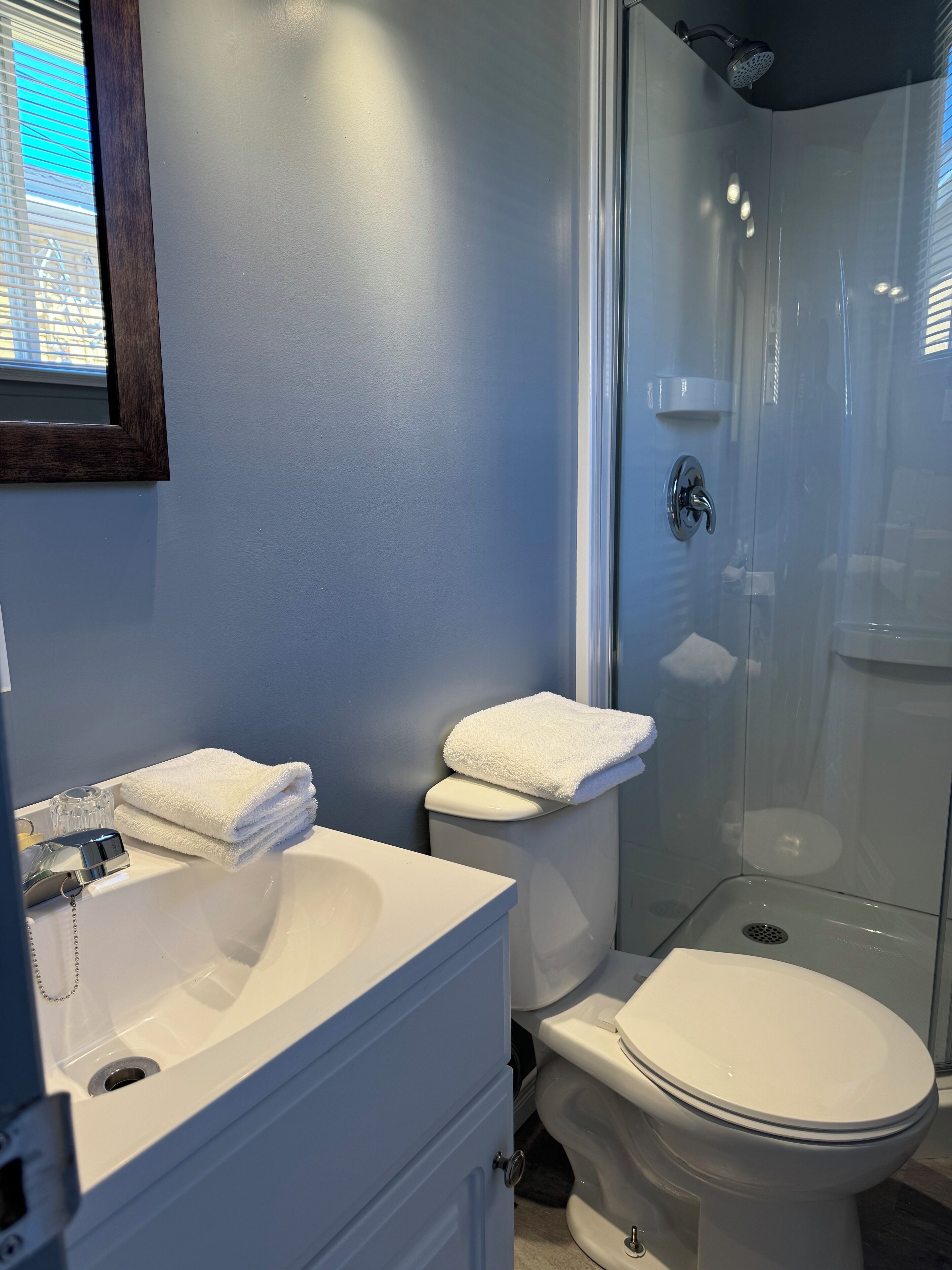 A bathroom with a white sink, two toilets, and a glass-enclosed shower.