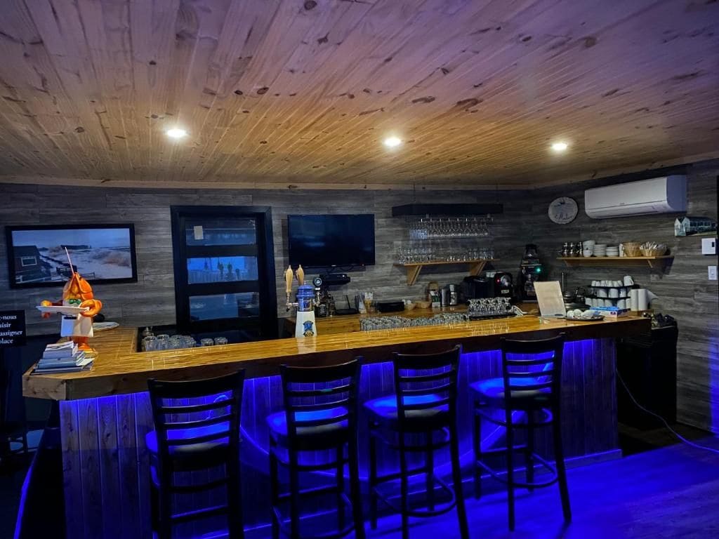 A bar area with a wooden ceiling, bar stools, and a counter with glasses and bottles.