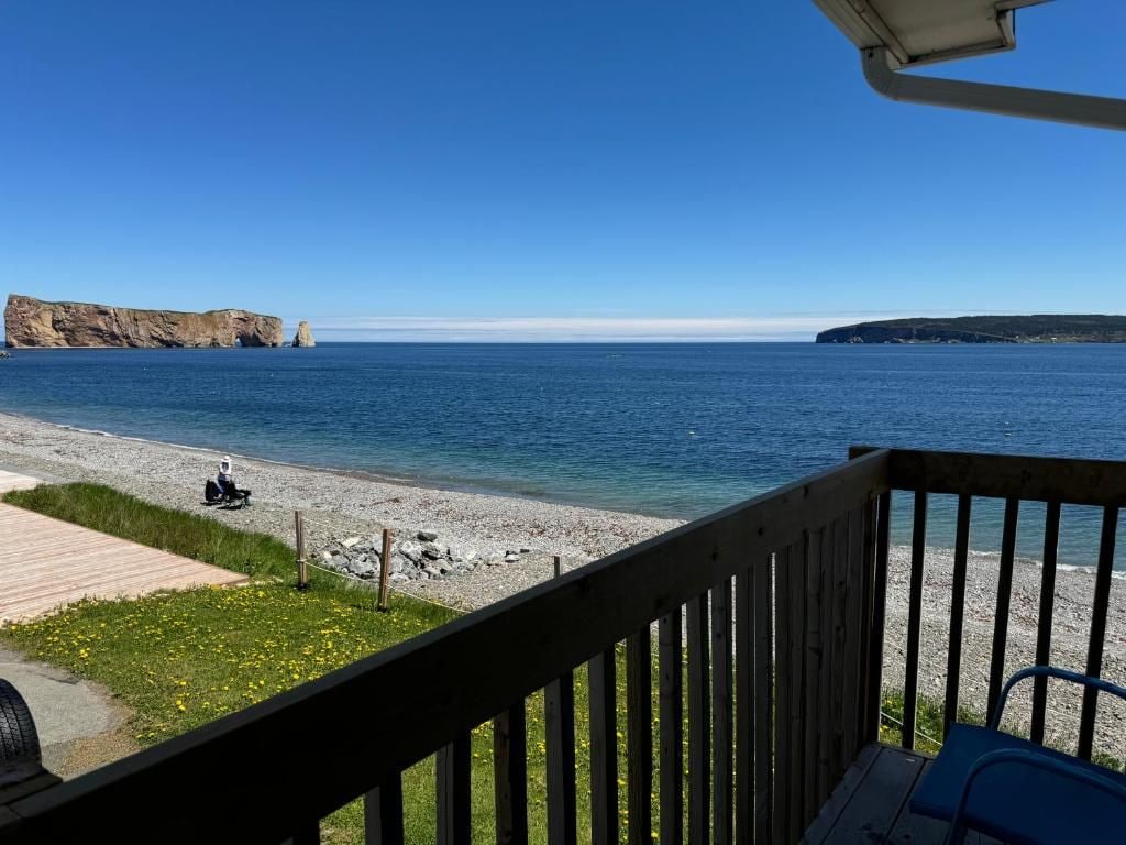 A wooden deck with a view of a calm sea and rocky coastline.