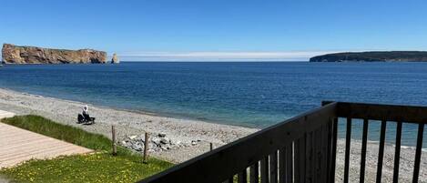 A wooden deck with a view of a calm sea and rocky coastline.