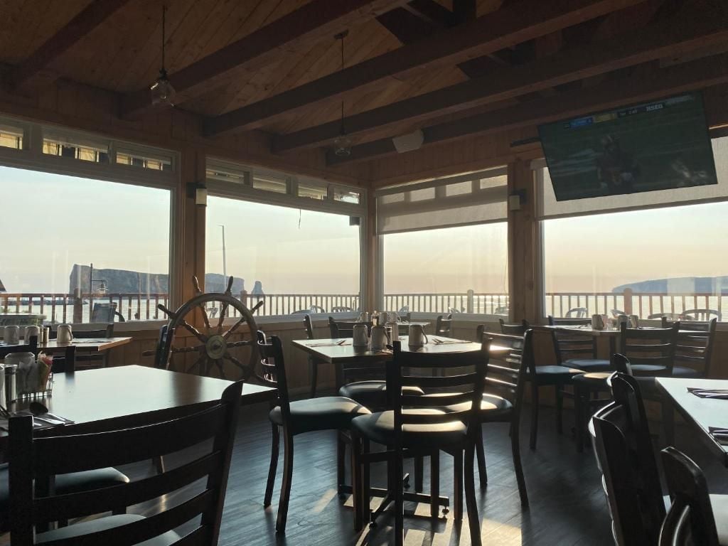 A restaurant with tables and chairs, large windows, and a view of the city.
