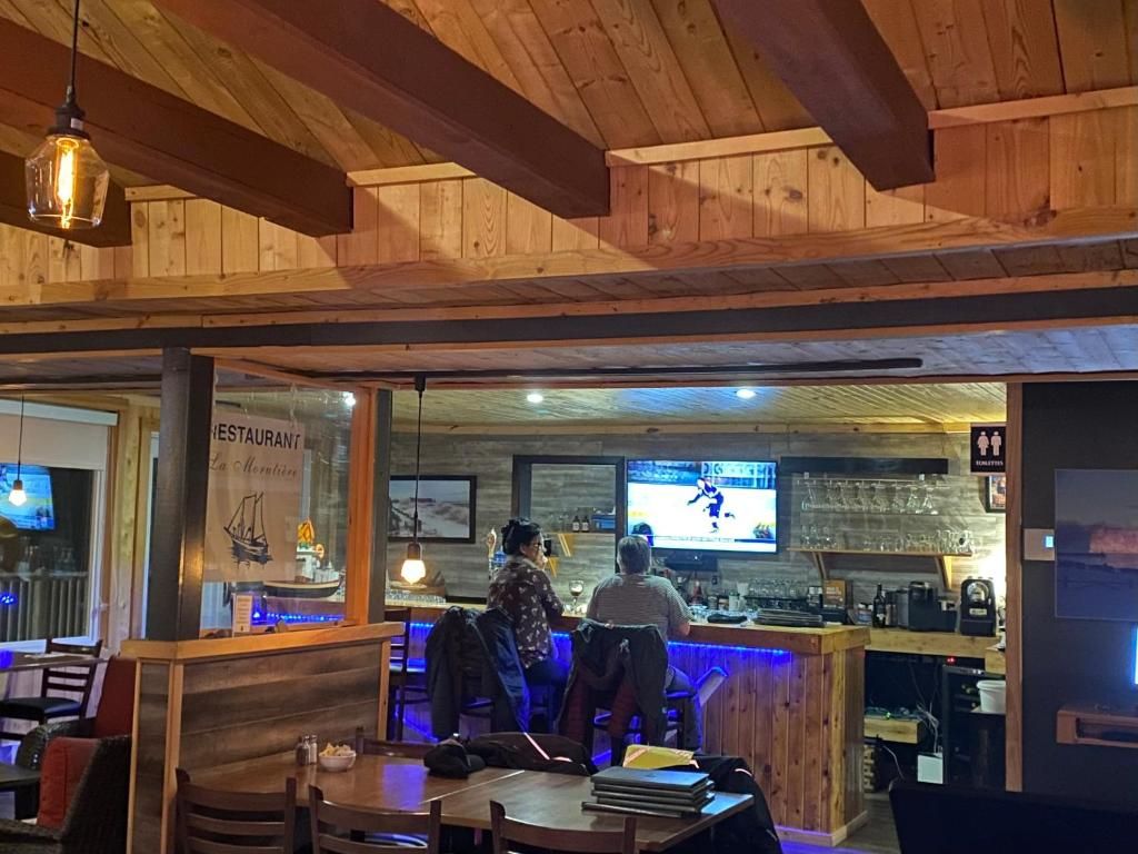 Ein Restaurantinneres mit Holzbalken, einer Bar und einem Bildschirm, der ein Sportereignis zeigt.