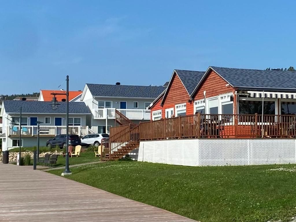 A residential area with houses, a wooden walkway, and a fenced yard.