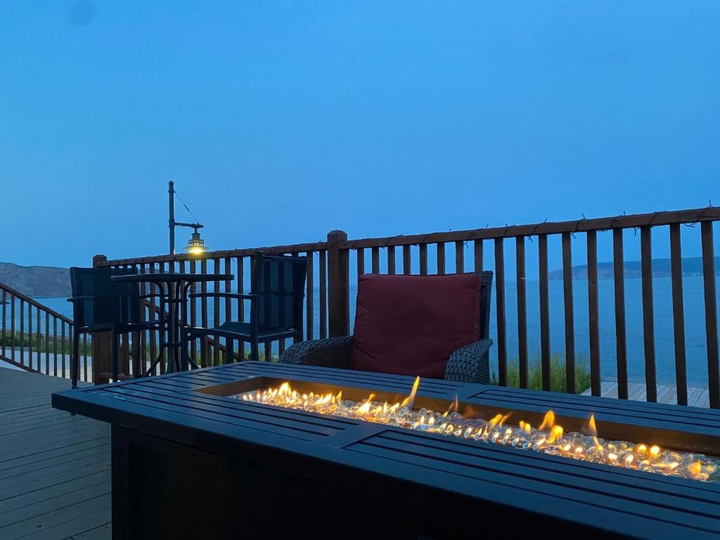 Een terras met een vuurplaats, buitenmeubilair en uitzicht op het water.