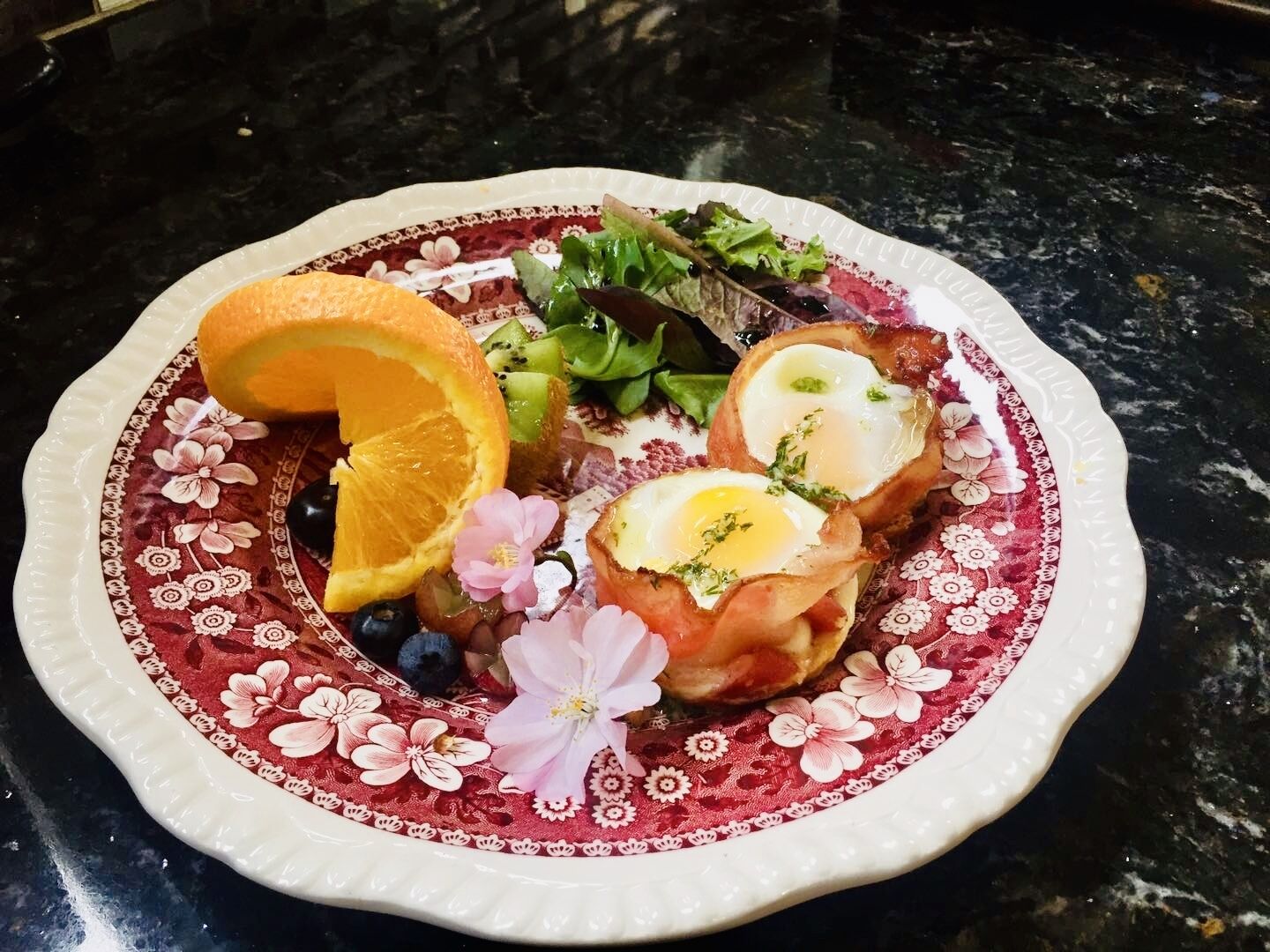 Une assiette contenant divers aliments, notamment des œufs, des fruits et des légumes verts.