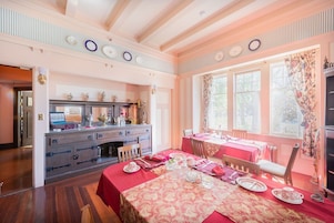 Un comedor con mantel rojo, sillas de madera y un mostrador de buffet con diversas opciones.