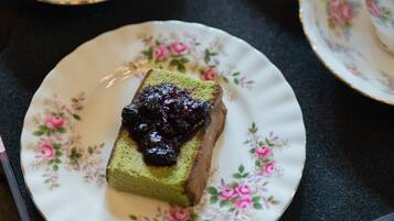 A tray with a teapot, teacups, and a slice of cake on a floral plate.