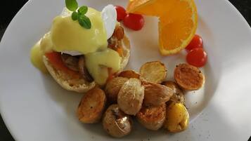 Une assiette contenant des œufs Bénédicte, des pommes de terre rôties et des tomates cerises.