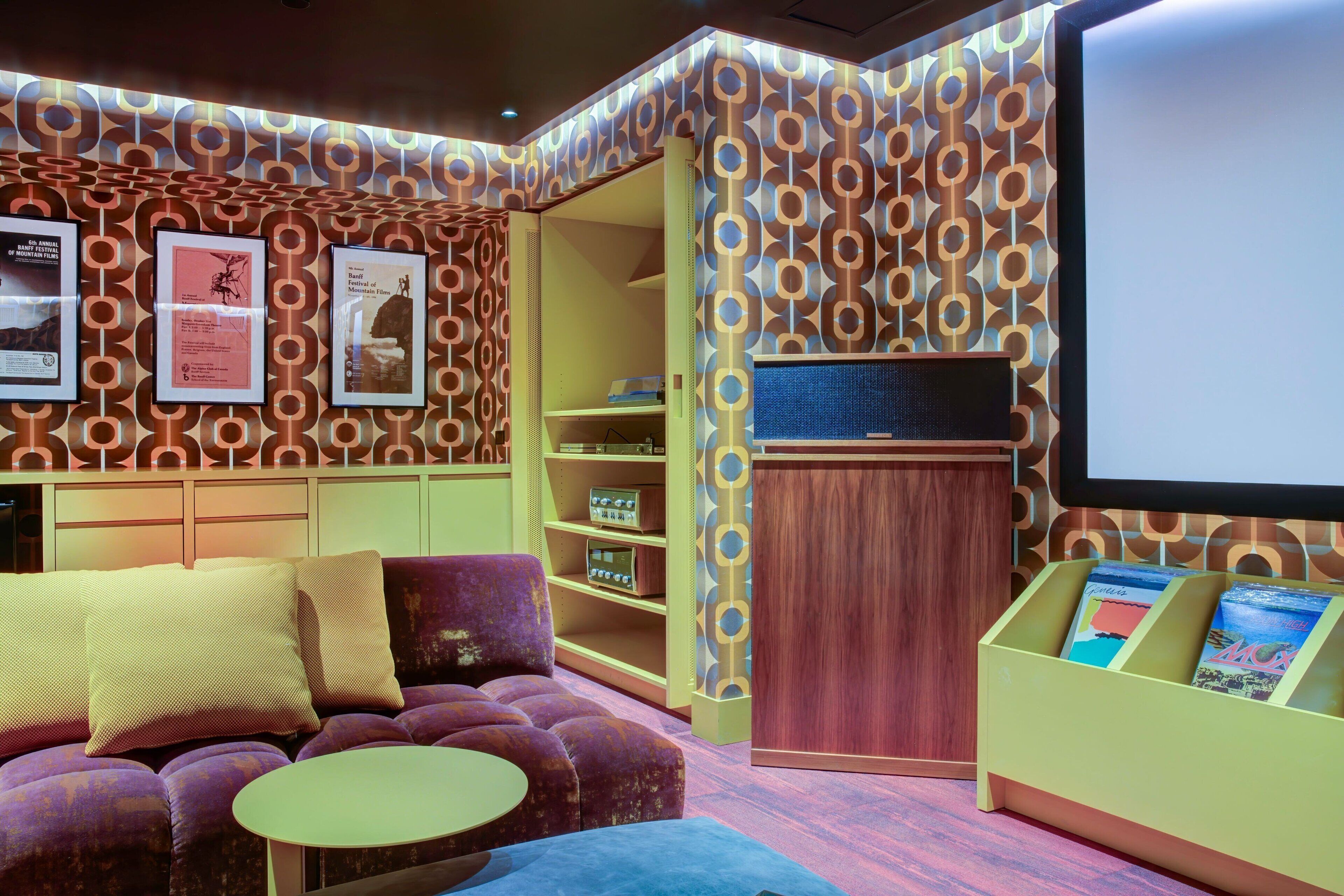 A cozy room with a purple sofa, a small round table, and a wooden cabinet with books.