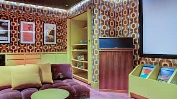 A cozy room with a purple sofa, a small round table, and a wooden cabinet with books.
