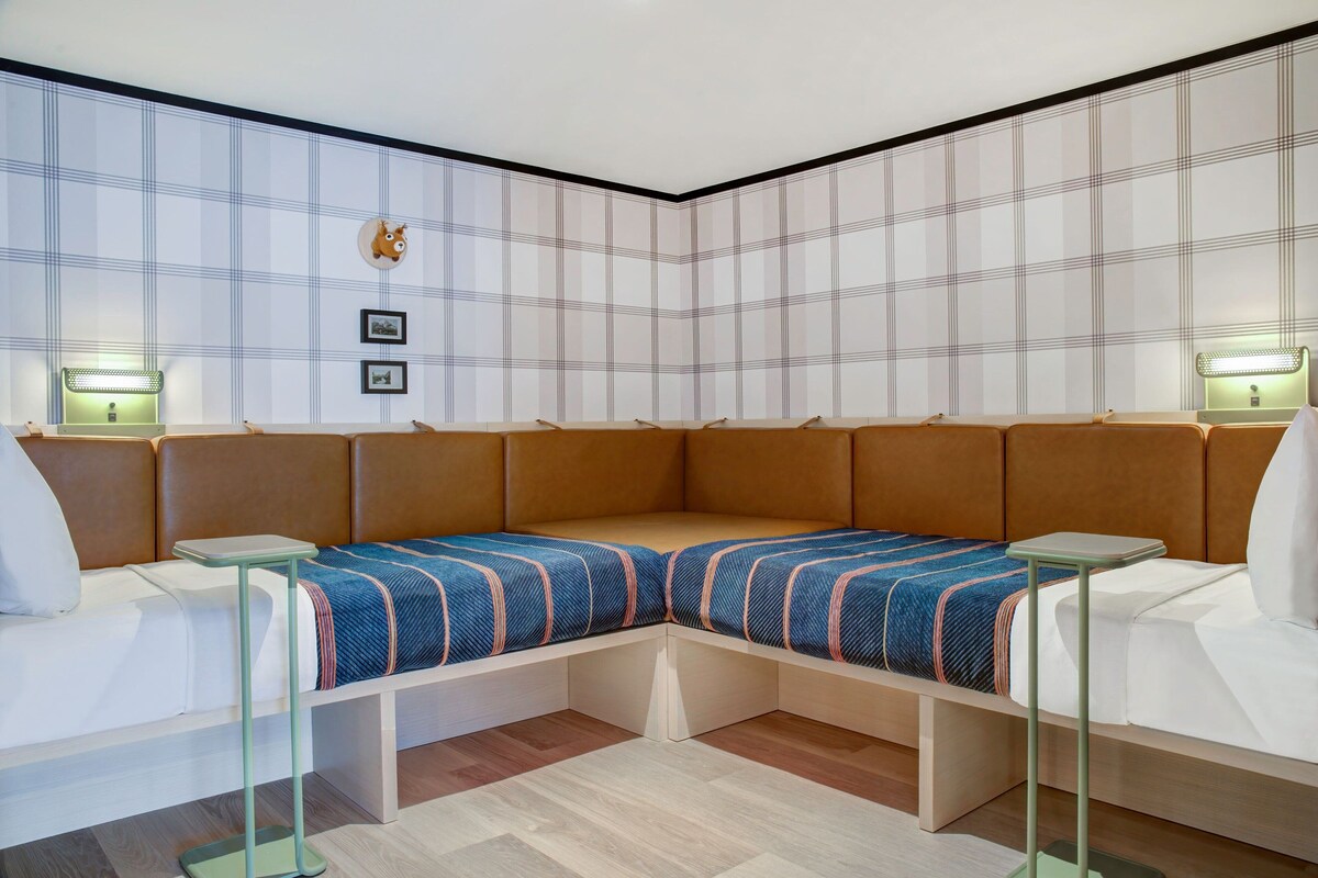 A modern room with a corner sofa, two side tables, and a wall-mounted light fixture.
