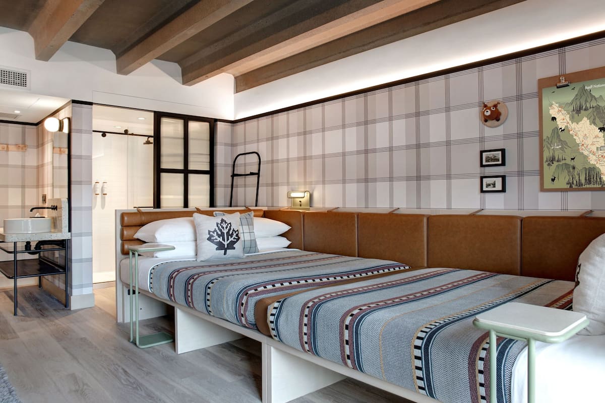 A modern bedroom with a large bed, bedside tables, a desk, and a wardrobe.