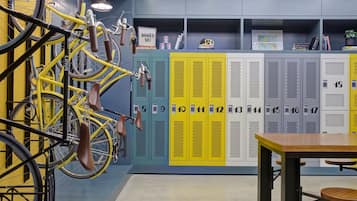 Vestidor amb armaris grocs numerats del vuit al disset, una taula i bicicletes amb seients marrons.