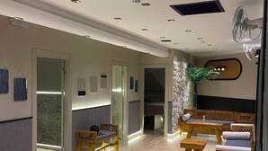 Un interior moderno con mostrador de recepción, asientos de madera y una pared decorativa de piedra.