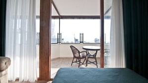 Un dormitorio con cama, una silla, una mesa y un balcón con vistas.