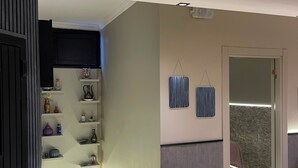 Un pasillo de diseño moderno, con un estante empotrado decorado con objetos, una lámpara de pared y una puerta que da a otra habitación.