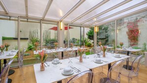 Un restaurante con paredes de vidrio transparente, mesas blancas y sillas transparentes.